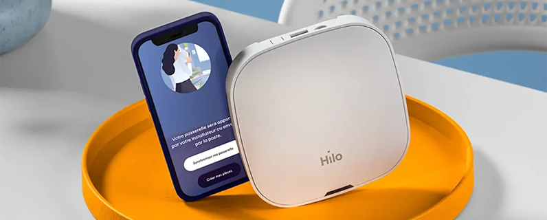 Les essentiels de la solution Hilo, soit la passerelle et un téléphone qui affiche l'application Hilo.